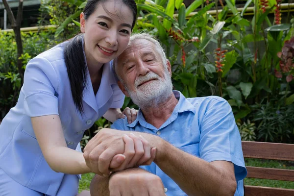 Hombre mayor felicidad y enfermera sonriente, cuida y discute — Foto de Stock