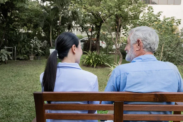 Vista posterior de la felicidad del hombre mayor sentado con la enfermera sonriente, ta — Foto de Stock