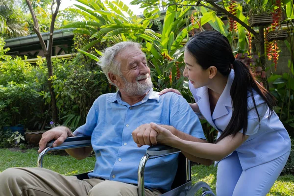 senior man happiness sitting on wheelchair with smiling nurse, t