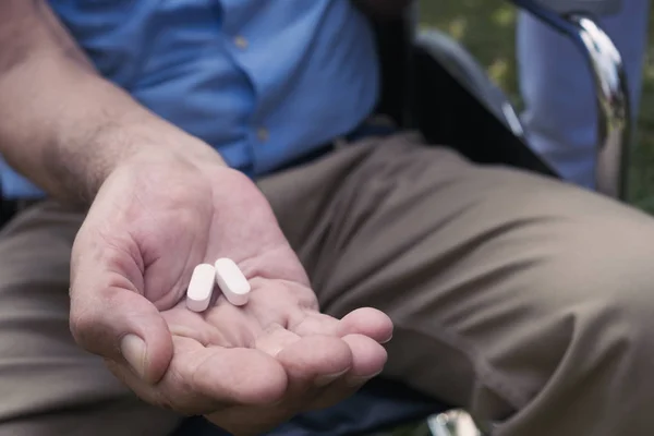 Main de l'homme âgé donner un médicament pour les soins de santé — Photo