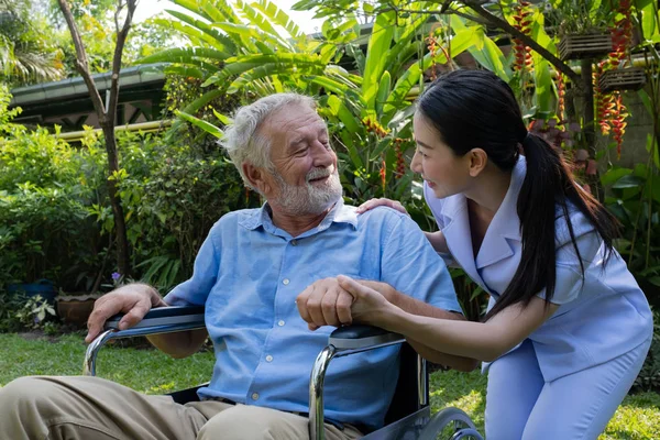 Senior man geluk zittend op rolstoel met lachende verpleegster, t — Stockfoto