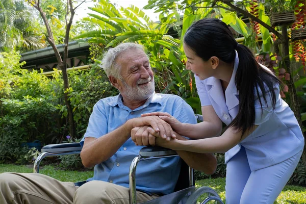Senior man geluk zittend op rolstoel met lachende verpleegster, t Rechtenvrije Stockfoto's
