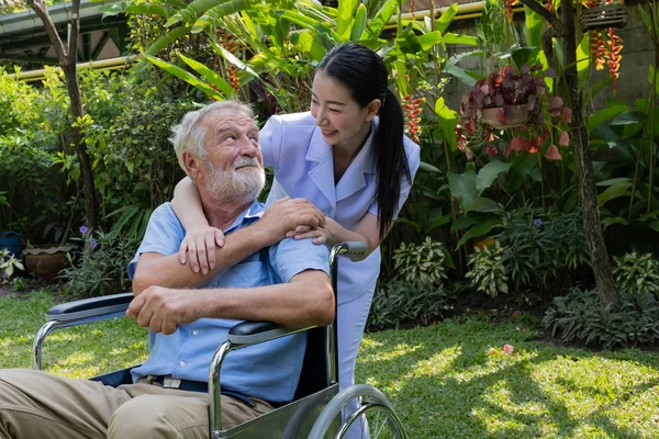 Senior man geluk zittend op rolstoel met lachende verpleegster, t — Stockfoto