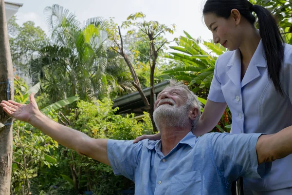 Senior man geluk zittend op rolstoel met lachende verpleegster, t — Stockfoto