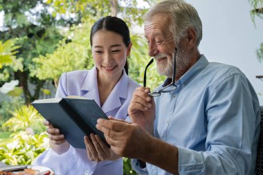 gülümseyen hemşire ile kıdemli adam mutluluk, b birlikte kitap okuyun