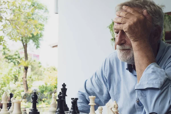 Hombre mayor jugando ajedrez en balcón cerca del jardín en el hogar de ancianos — Foto de Stock