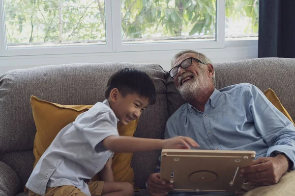 Senior man lycka och barnbarn sitter på soffan och pl — Stockfoto
