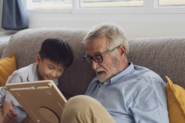 Senior man geluk en kleinzoon zitten op de Bank en pl — Stockfoto