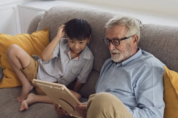 Senior man geluk en kleinzoon zitten op de Bank en pl — Stockfoto