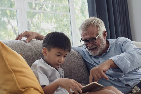 Senior man geluk en kleinzoon zitten op de Bank en pl — Stockfoto