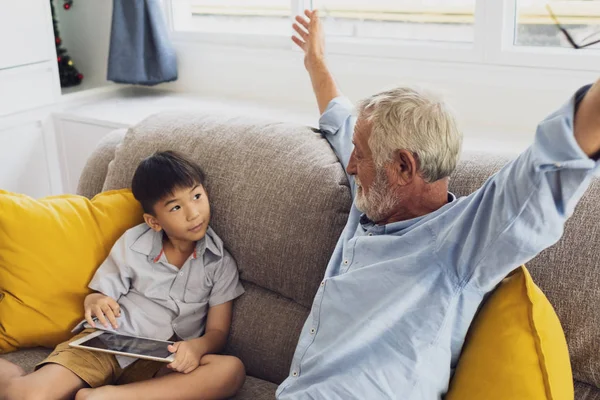 Senior man geluk en kleinzoon zitten op de Bank en pl — Stockfoto