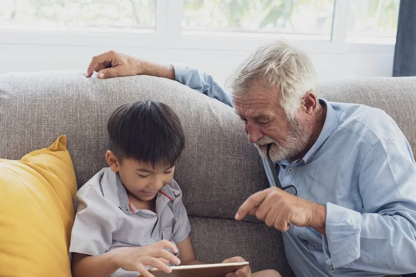 Senior man geluk en kleinzoon zitten op de Bank en pl — Stockfoto