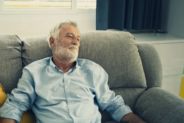 Starszy mężczyzna siedzi na kanapie i smutny w pokoju dziennym dla relaxi — Zdjęcie stockowe