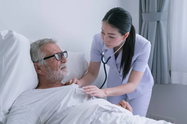 Senior man med leende sjuksköterska, tar hand och diskussion efter h — Stockfoto