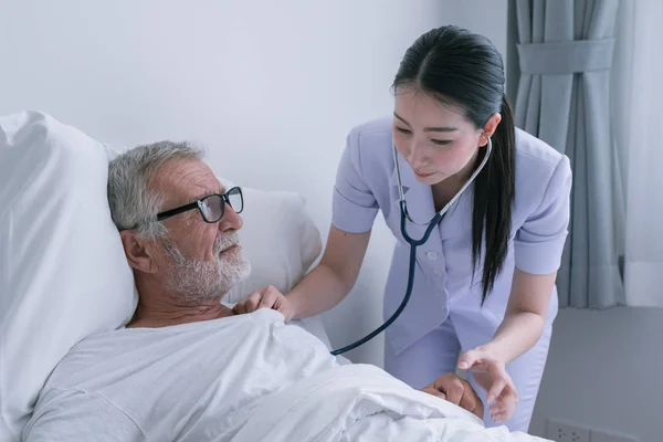 Senior man med leende sjuksköterska, tar hand och diskussion efter h — Stockfoto