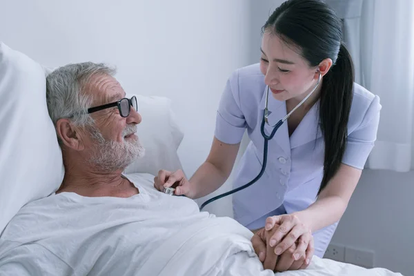 Senior man med leende sjuksköterska, tar hand och diskussion efter h — Stockfoto