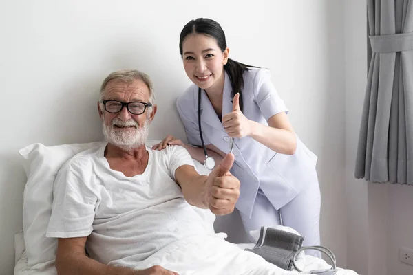 Senior man med leende sjuksköterska, tar hand och diskussion efter h — Stockfoto