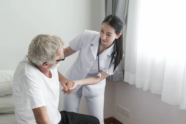 Senior man ryggvärk med leende sjuksköterska, tar hand och mi — Stockfoto
