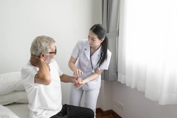 Senior man ryggvärk med leende sjuksköterska, tar hand och mi — Stockfoto