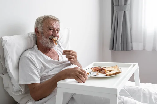 Senior man med leende sjuksköterska, tar hand frukost och mi — Stockfoto