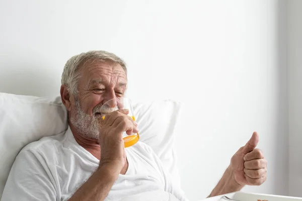 Seniorchef mit lächelndem und aufmunterndem Lächeln auf dem Bett im Pflegeheim — Stockfoto