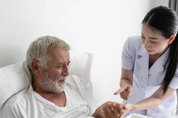 Sjuksköterska ge piller till Senior man efter frukost och diskussion om — Stockfoto