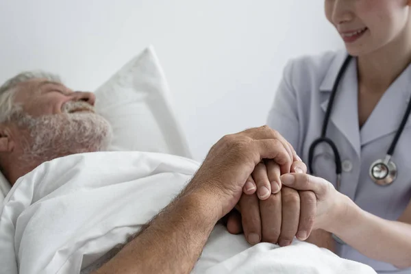 Рука пожилого человека с улыбающейся медсестрой, заботится и веселится на б — стоковое фото