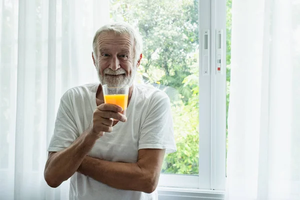 先輩男性の笑顔と前にオレンジジューススタンドのグラスを保持 — ストック写真