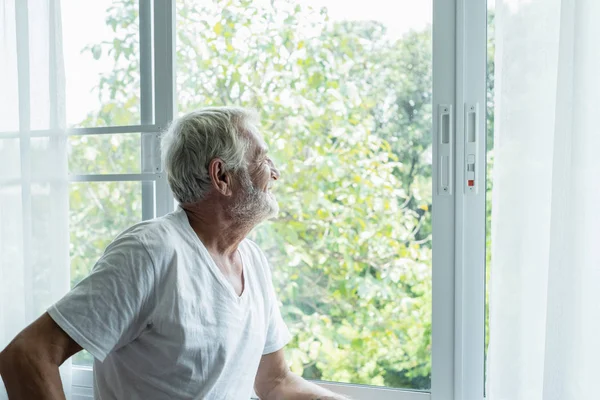 Starszy mężczyzna myślenia i patrząc poza oknem w białym pokoju — Zdjęcie stockowe