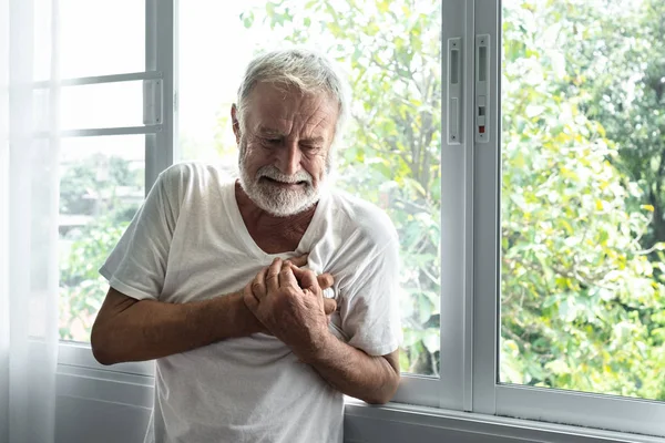 Omul în vârstă stă și simte atac de cord singur în camera albă — Fotografie, imagine de stoc