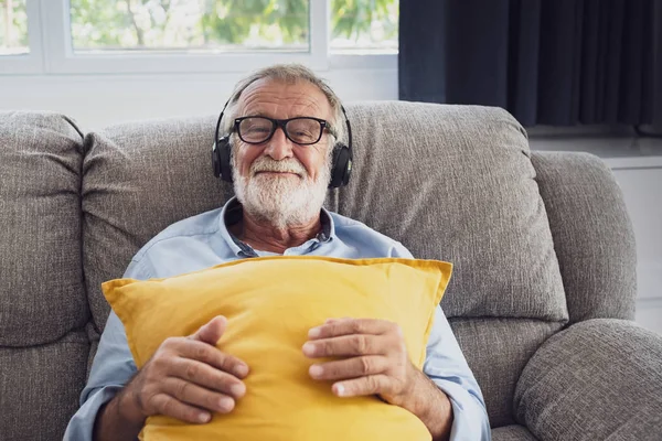 Senior man geluk zittend op de Bank en luisteren muziek met wit Stockfoto