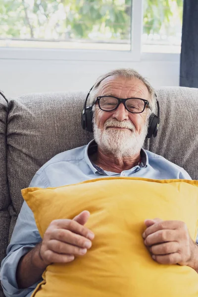 Senior man geluk zittend op de Bank en luisteren muziek met wit Stockfoto