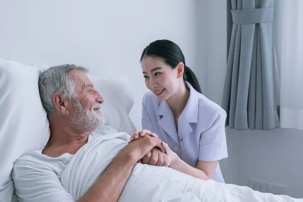 Senior man met lachende verpleegster, neemt zorg en discussie en Che Rechtenvrije Stockafbeeldingen