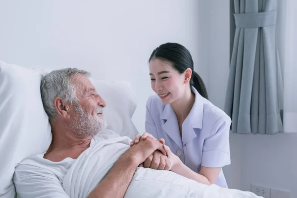 Senior man met lachende verpleegster, neemt zorg en discussie en Che Stockafbeelding