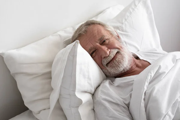 Senior man slaap met glimlach op bed in de kamer Rechtenvrije Stockfoto's