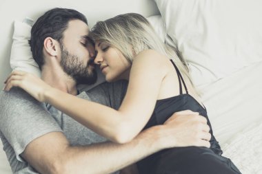 Aşk ta sevgi dolu mutlu çift gülümseme ve yatakta birbirlerine sarılmak,