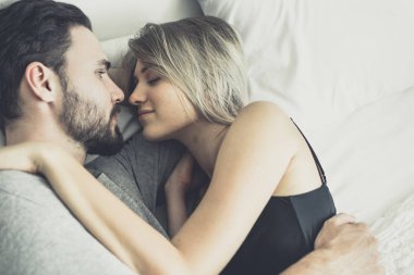 Aşk ta sevgi dolu mutlu çift gülümseme ve yatakta birbirlerine sarılmak,