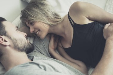 Aşk ta sevgi dolu mutlu çift gülümseme ve yatakta birbirlerine sarılmak,