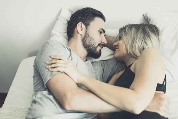 Kärleksfull lycklig par i kärlek leende och krama varandra på sängen, — Stockfoto