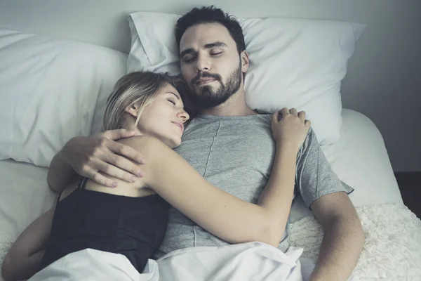 Liefdevolle gelukkig paar in liefde glimlach en knuffel elkaar op het bed, — Stockfoto