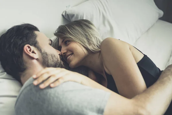 Liefdevolle gelukkig paar in liefde glimlach en knuffel elkaar op het bed, Stockfoto