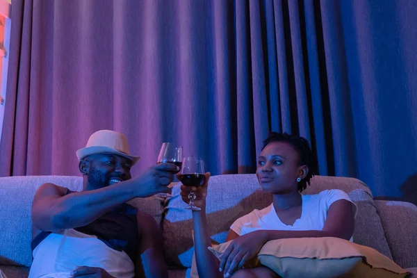 Usměvavý muž a žena držící sklenici vína sedící na pohovce v t — Stock fotografie