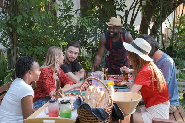 Gruppe glücklicher Freunde isst und trinkt Bier beim Grillen lizenzfreie Stockfotos