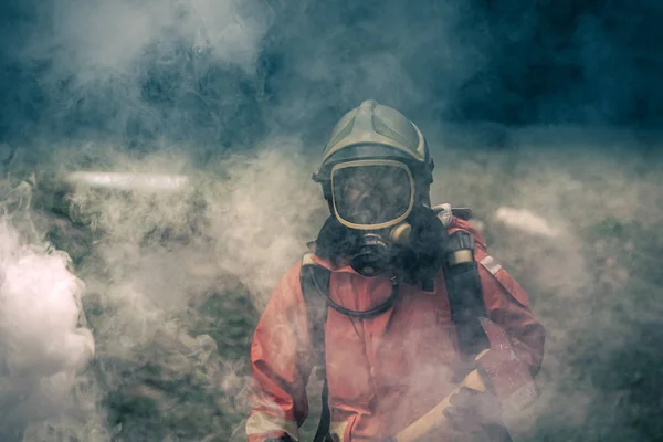 Brandweerman draagt een veiligheidssuite en loopt naar brandschade gebied Stockafbeelding