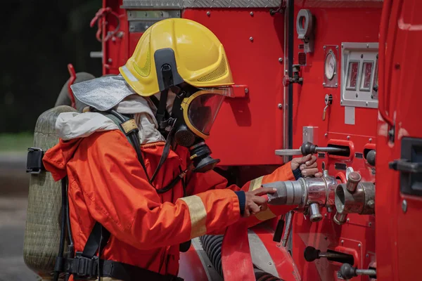 Brandweerman met veiligheidssuite gebruikt het hogedrukvat. Stockfoto