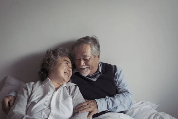 上了年纪的夫妇白头偕老地坐在床上 躺在卧室的白色毛毯里拥抱在一起 退休后的医疗保健与爱情生活方式的概念 — 图库照片