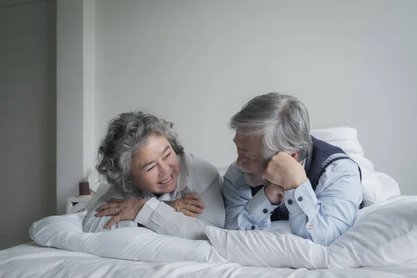 上了年纪的夫妇白头偕老 男女都睡在床上 在卧室的白色毛毯里笑着 退休后的医疗保健与爱情生活方式的概念 — 图库照片