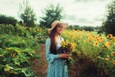 Ayçiçekleri arasında tarlada yürüyün