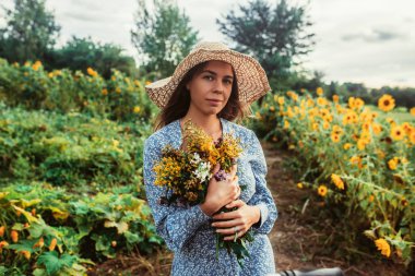 Ayçiçekleri arasında tarlada yürüyün