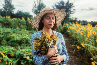 Ayçiçekleri arasında tarlada yürüyün